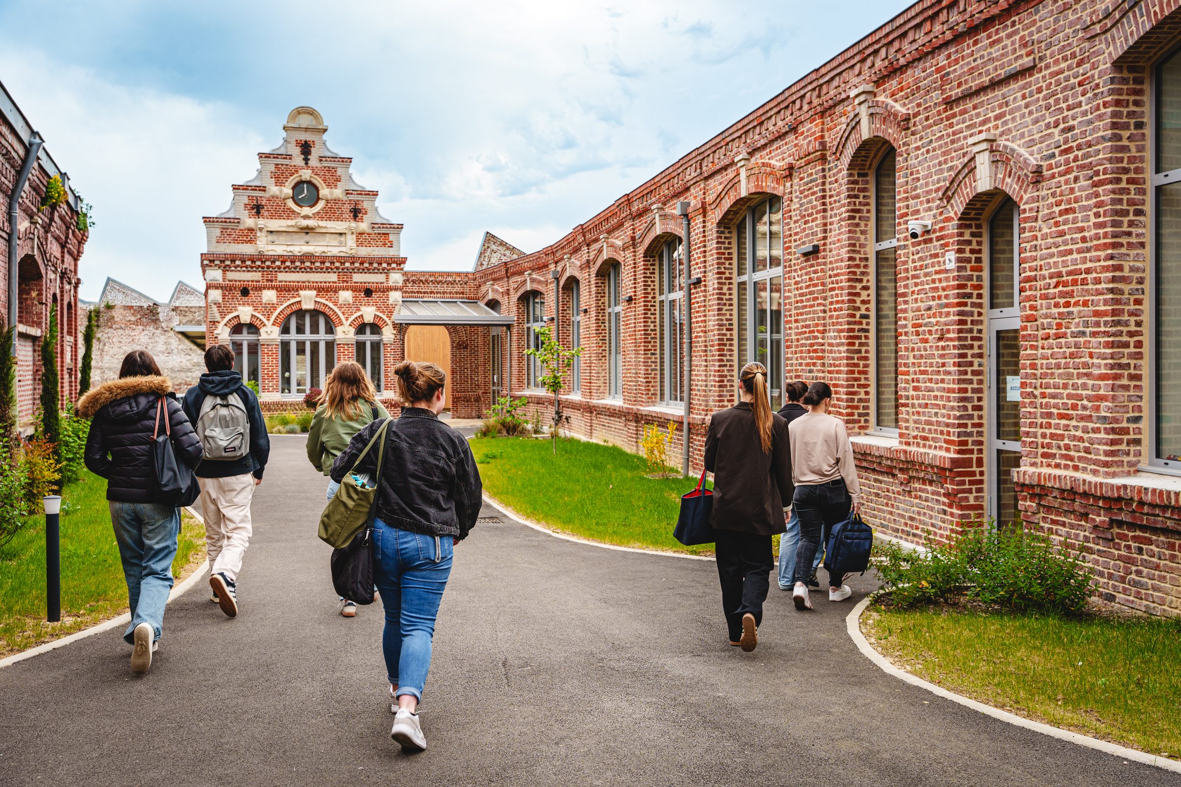 Étudiants du sup' marchant dans l'allée entre les bâtiments en briques du campus